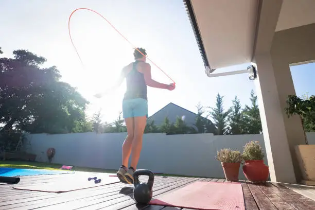A women keeps fit at home by doing some jump rope. Active woman doing some exercise at home to keep fit and healthy