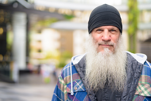 Portrait of mature handsome bearded hipster man in the city streets outdoors