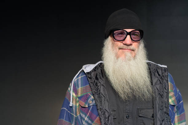 istock Mature bearded hipster man with sunglasses thinking against black wall 1219288389