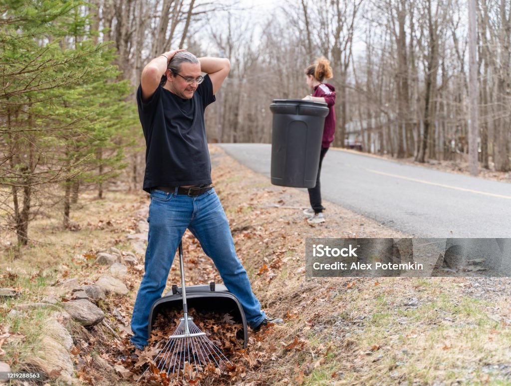 50Jarige Man Met Paardenstaart Die De Achtertuin Schoonmaakt Van Oude Bladeren In De Lente Zijn Tienerdochter Helpt Hem Stockfoto En Meer Beelden Van Herfst - Istock