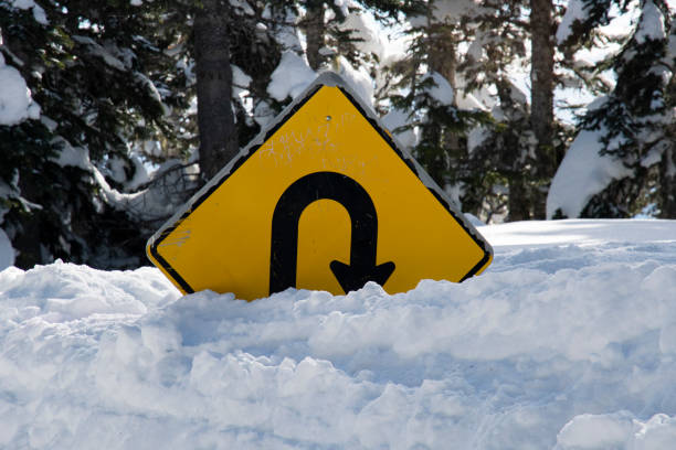 istock Road sign in the snow, forest, u turn 1219296955