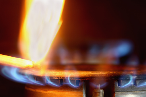 a lighted match at the gas stove