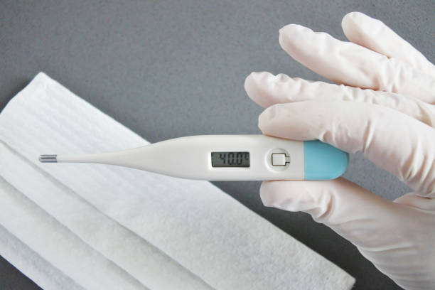 istock Person wearing protective gloves looking at thermometer showing high temperature. 1219298167