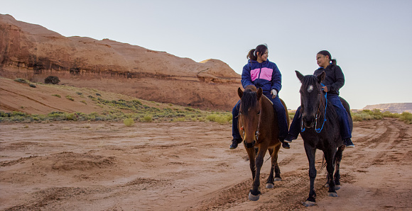 A Ten-Year-Old Native American Boy (Navajo) Rides His Horse and Talks with His Teenaged Sister in the Monument Valley Desert of Arizona/Utah Next to a Large Rock Formation