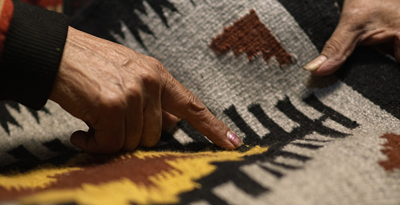 A Native American Woman's Hands (Navajo) Point to Designs on a Navajo Blanket