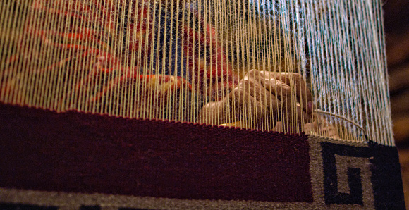 A Native American (Navajo) Woman's Hands Weave at a Loom Indoors