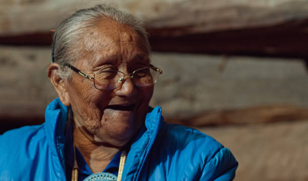 eine indianerin (navajo) frau in ihren achtzigern spricht und lacht mit anderen - navajo american culture indigenous culture women stock-fotos und bilder