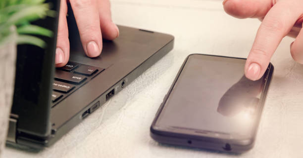istock businesswoman types on modern black smartphone and on notebook sitting at white table 1219299080