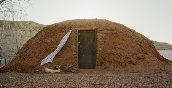 Outside of a Hogan (Navajo Hut) with a Large Rock Formation Behind It