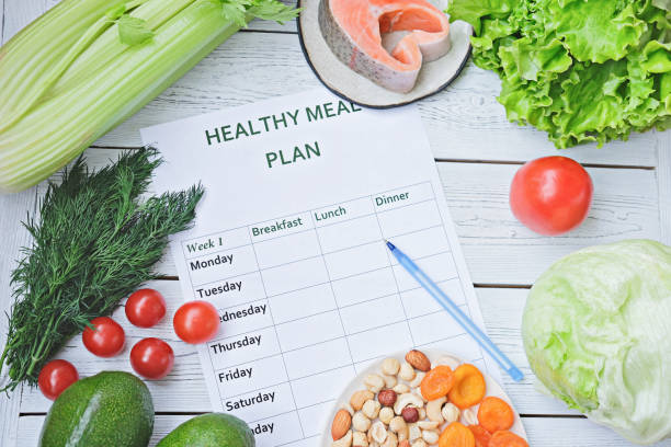 istock meal plan for a week on a table among tomatoes, fish, nuts, greens and avocado. healthy eating, dieting, slimming and weigh loss concept 1219300663