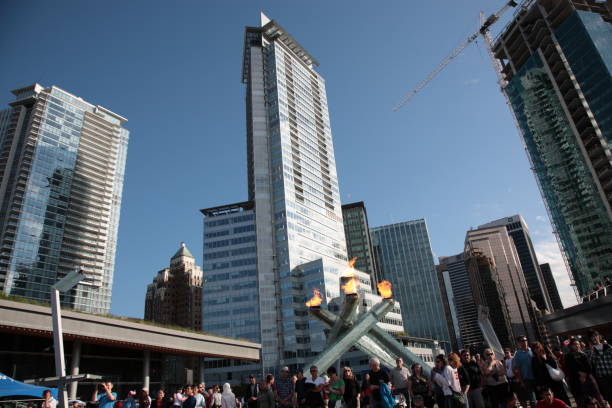 People and the 2010 Olympic Cauldron burning celebrating 2011 Canada day at Vancouver coal harbour. The Cauldron is located at Jack Poole Plaza in downtown Vancouver, Canada.