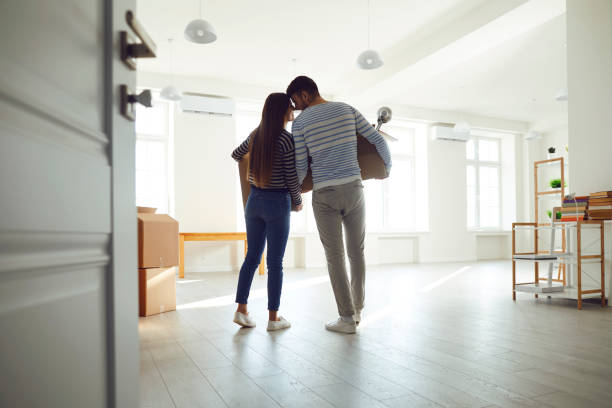 vue arrière en mouvement. famille de couples jeunes avec des boîtes pour se déplacer dans une nouvelle salle de maison. - people house home interior construction photos et images de collection