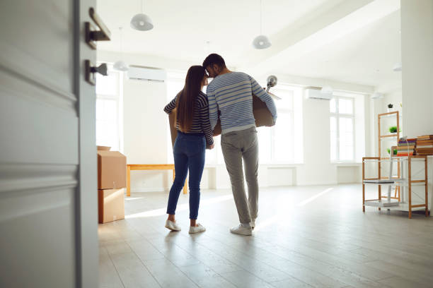 Rear view moving. Young couple family with boxes to move in a new house room. Rear view moving. Young couple family with boxes to move in a new house room. Buying sale, rent, real estate mortgage. home ownership stock pictures, royalty-free photos & images