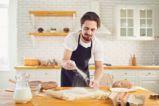 istock Baker male bearded man makes fresh bread dough at a table in the bakery kitchen. 1219302709