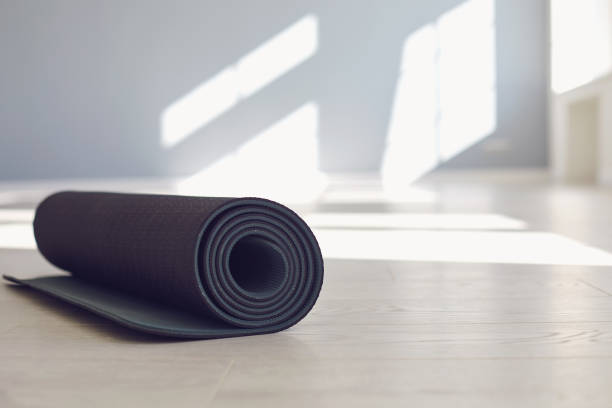 Black yoga mat on the floor of a bright sunny studio. Black yoga mat on the floor of a bright sunny studio. The concept of an active lifestyle of sports life sports fitness yoga pilates meditation relaxation relaxation gym. mat stock pictures, royalty-free photos & images