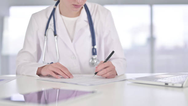 istock Close up of Young Doctor doing Paperwork in Office 1219304775