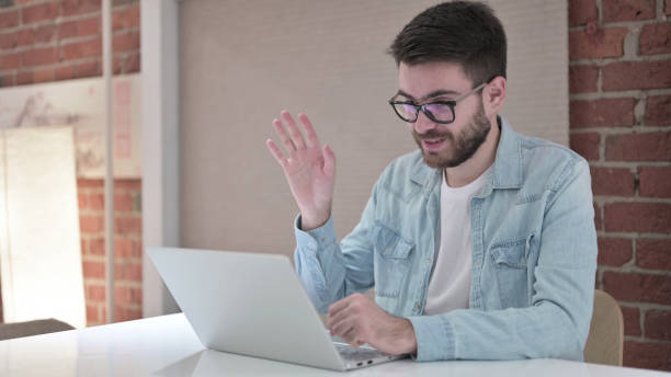 wesoły młody człowiek w okularach robi video chat na laptopie - 15831 zdjęcia i obrazy z banku zdjęć