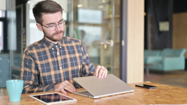 istock Young Male Designer Closing Laptop to Leave Office 1219311108