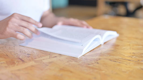 istock Close Up of Hands Skimming a Book 1219311846