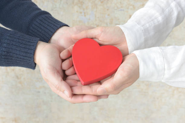 男性と女性の手で覆われた心臓オブジェクト - サポート ストックフォトと画像
