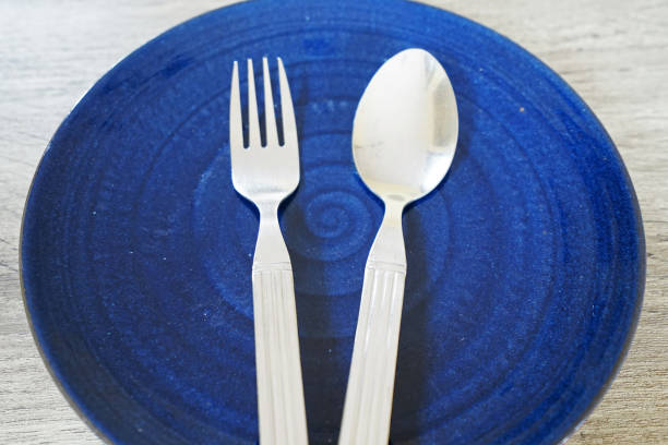 istock Close up blue ceramic porcelain dish with stainless steel fork and spoon 1219314721