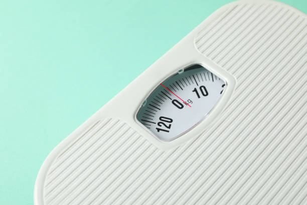 istock White scales on mint background. Weight loss concept 1219315495