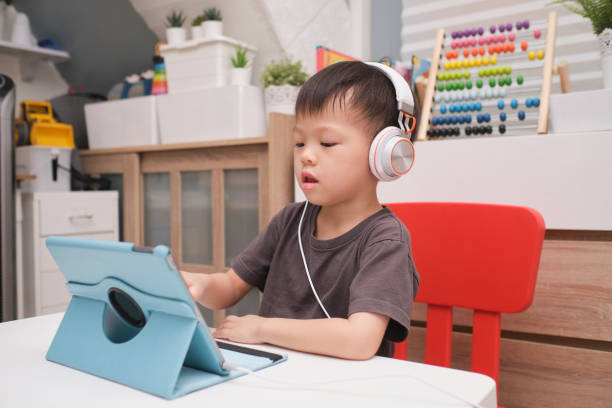 bambino asiatico di 4 anni bambino che utilizza tablet pc computer, bambino a casa durante la crisi sanitaria covid-19, apprendimento a distanza, attività per il concetto di asilo - toddler music asian ethnicity child foto e immagini stock