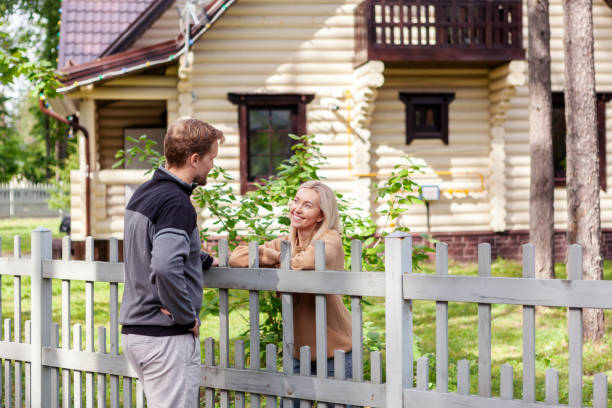Middle aged man meeting smiling female neighbor in countryside and talking cheerfully to her over fence Middle aged man meeting smiling female neighbor in countryside and talking cheerfully to her over fence neighbour stock pictures, royalty-free photos & images