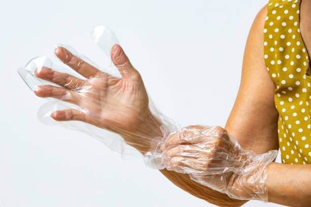 istock Senior woman's hands wearing disposable protective plastic gloves on grey background, Close up shot, Prevention from covid19, Coronavirus, Bacteria, Healthcare 1219322446