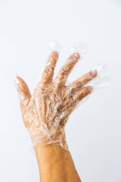 istock Senior woman's hands wearing disposable protective plastic glove on grey background, Close up shot, Prevention from covid19, Coronavirus, Bacteria, Healthcare 1219322450