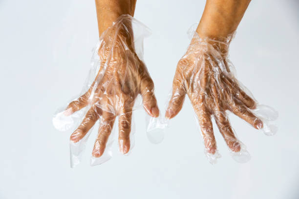 istock Senior woman's hands wearing disposable protective plastic gloves on grey background, Close up shot, Prevention from covid19, Coronavirus, Bacteria, Healthcare 1219322456