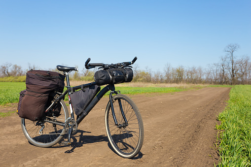 touristic travel bicycle with bags on a ground road among a fields
