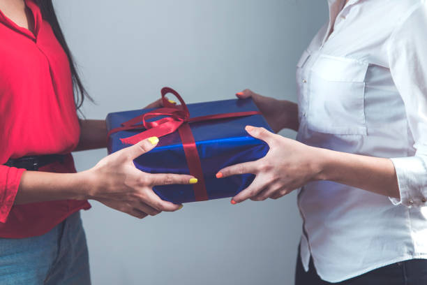 istock two woman hand holding gift box 1219326515