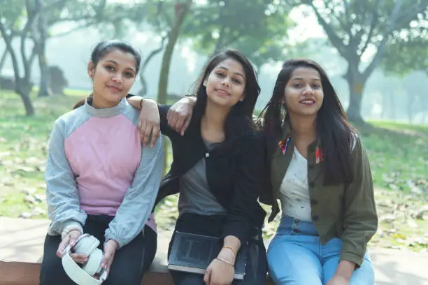 Photo of Group of multi ethnic happy female friends sitting on a bench in the park and enjoying in nature.