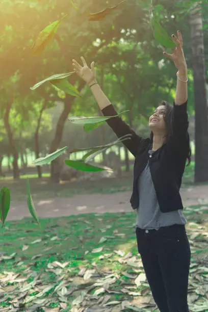 Photo of Beautiful young girl throwing leaves in a park and enjoying in nature