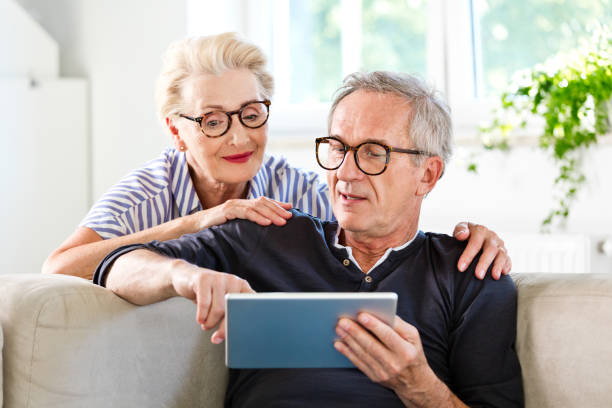 starsza para oglądająca cyfrowy tablet razem w domu - senior adult women adult tan zdjęcia i obrazy z banku zdjęć