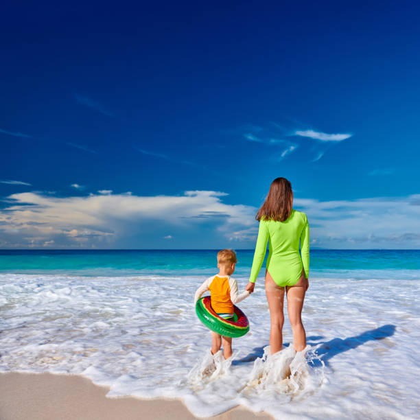 Three year old toddler boy on beach with mother. Summer family vacation at at Seychelles, Mahe.