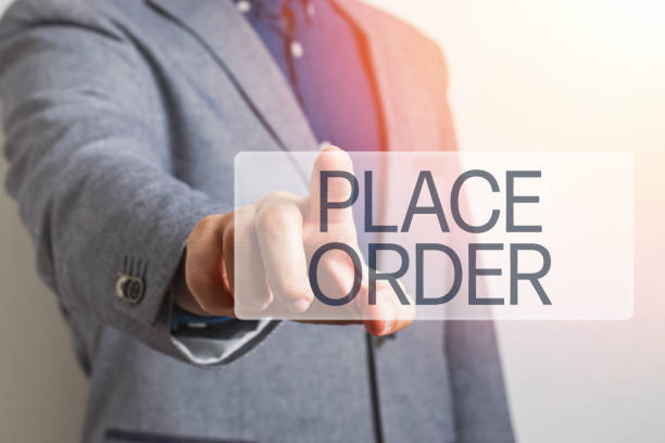istock Man's hand with point finger pushing virtual online button with text Place Order close-up. 1219333079