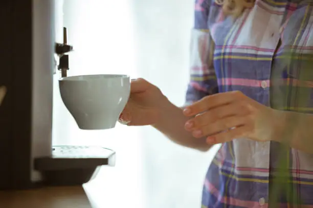 Close up of female hands making coffee on coffee-machine at home or cafe. Concept of working, studying at home, domestic life. Home comfort, quarantine, isolation. Aroma hot tasty drink.