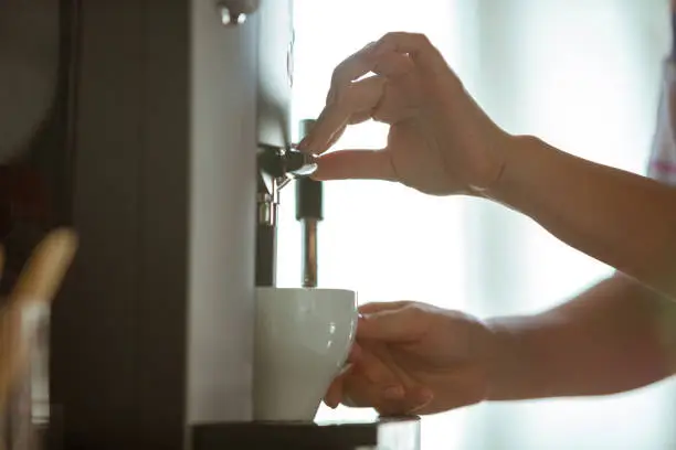 Close up of female hands making coffee on coffee-machine at home or cafe. Concept of working, studying at home, domestic life. Home comfort, quarantine, isolation. Aroma hot tasty drink.