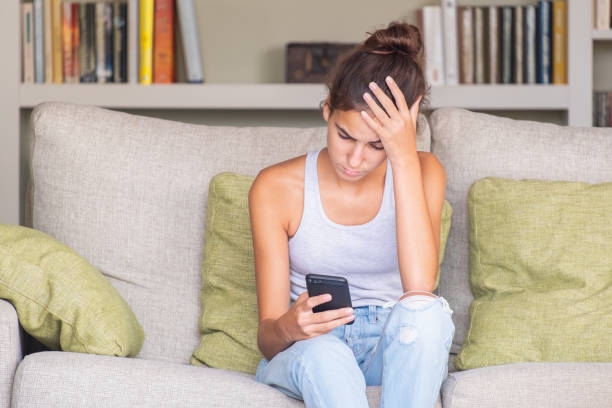 istock upset young girl reading a message in a smart phone 1219335565