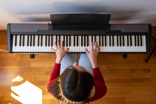 istock beautiful woman playing piano 1219336065