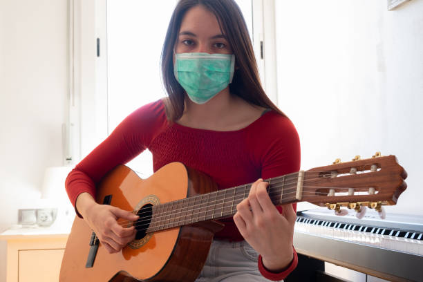 istock girl wearing face mask with guitar 1219336076