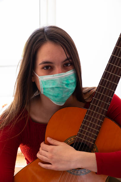 istock girl wearing face mask with guitar 1219336094