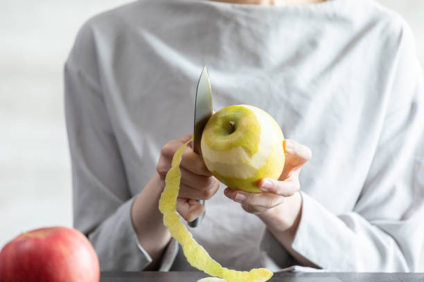 istock Young woman peeling an apple in the room 1219337799