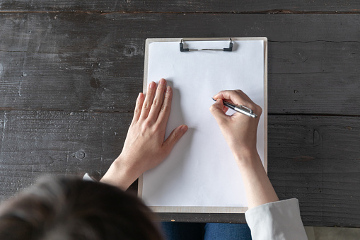 Hand of a young woman signing a contract in a room