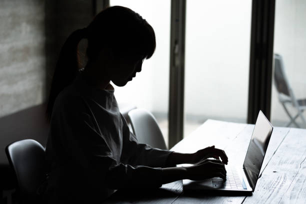 istock Hand of a young woman working on a computer in a dark room 1219338480