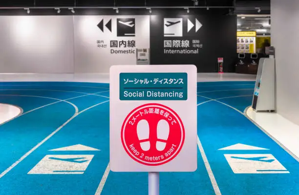 Social distancing sign with footprints icon urging travelers to keep 2 meters apart in the  departure terminal 3 of International Airport in Tokyo, Japan.