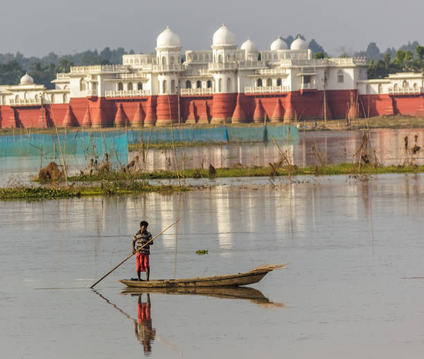 A fisherman rowing a fishing boat in front of the Neermahal Palace Melaghar, Tripura/India - December 6 2017 - A fisherman rows his boat in the waters of the Rudrasagar lake. Neermahal, the ancient lake palace, form the backdrop. lake palace stock pictures, royalty-free photos & images