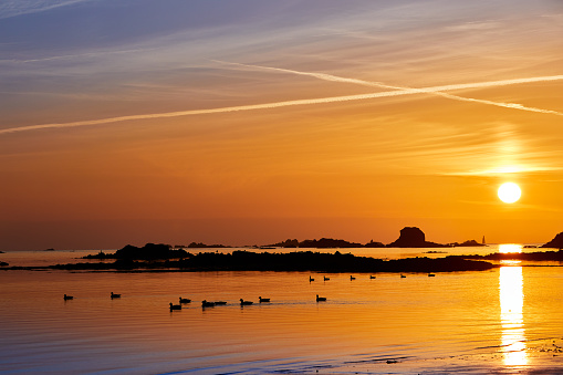 Sunset at St Clements Bay, Jersey CI with smooth sea, rocks, ducks and demi de pas.